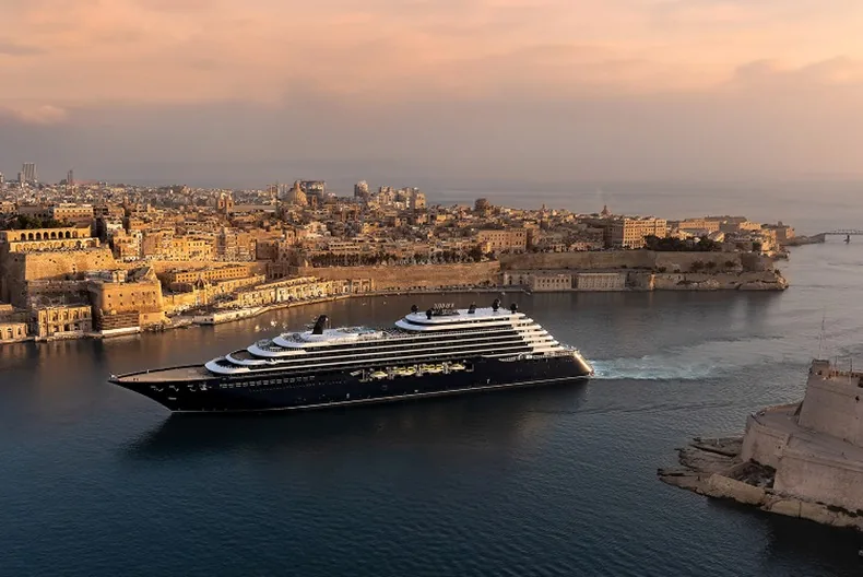 Ilma of The Ritz-Carlton Yacht Collection passing an old harbour city in warm light